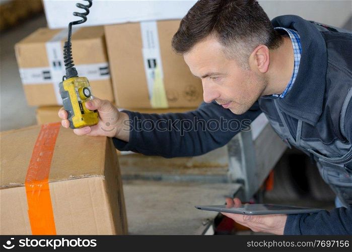 deliveryman in warehouse loading cardboard boxes into truck