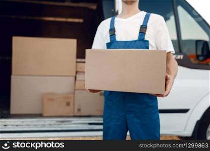 Deliveryman with carton box at the car, delivery service. Man in uniform holding cardboard package, male deliver, courier job. Deliveryman with carton box at the car, delivery