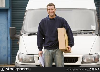 Deliveryperson standing with van holding clipboard and box smiling
