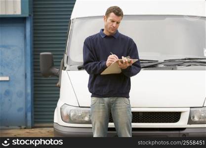 Deliveryperson standing with van writing in clipboard