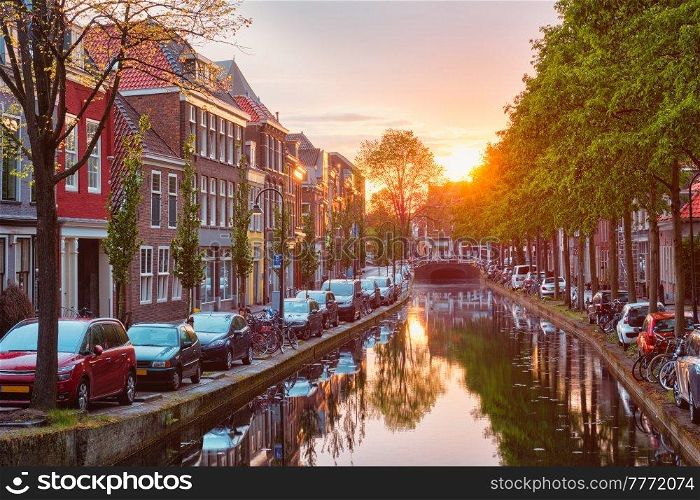 Delt canal with old houses and cars parked along on sunset. Delft, Netherlands. Delt canal with old houses and cars parked along on sunset
