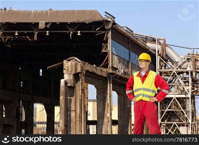 Demolition engineer standing in front of an old factory building, being torn down