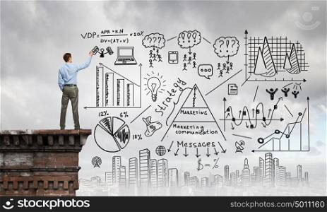 Demonstrating business success strategy. Back view of businessman drawing plan sketches on wall