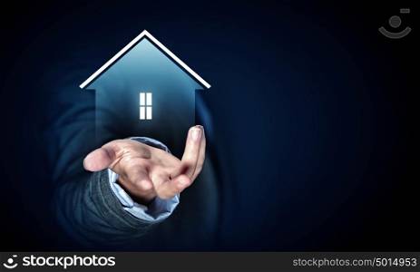 Demonstrating house concept. Close up of businesswoman holding real estate icon in palm on dark background