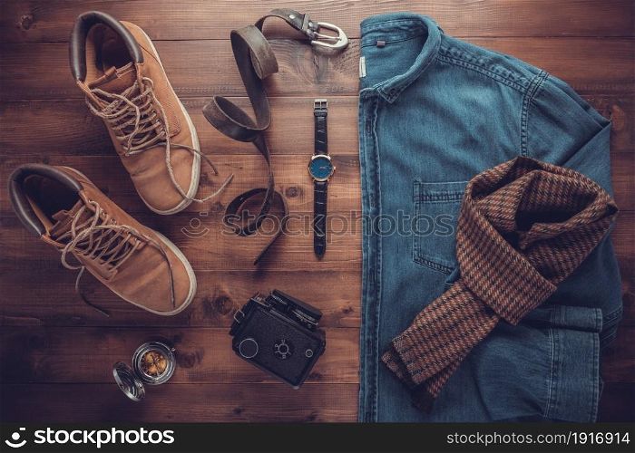 Denim jeans shirt and old boots with leather bag at wood table. Travel concept of retro clothes