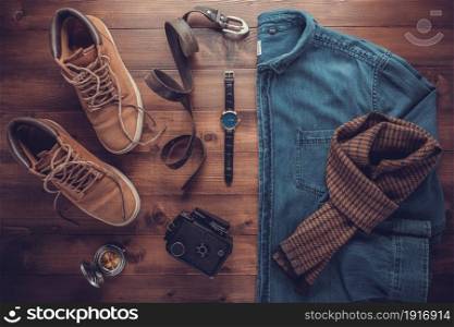 Denim jeans shirt and old boots with leather bag at wood table. Travel concept of retro clothes