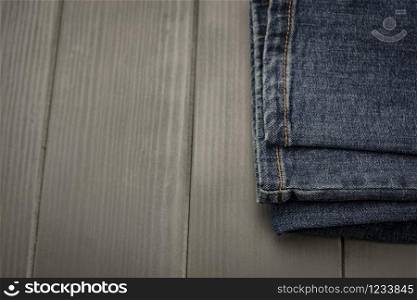 Denim pants with gold stitching on gray wooden background