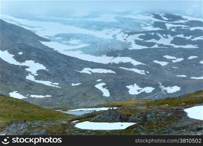 Dense fog and summer mountain landscape with lake and snow (Norway, not far Nigardsbreen glacier).