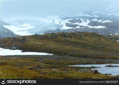 Dense fog and summer mountain landscape with lake and snow (Norway, not far Nigardsbreen glacier).