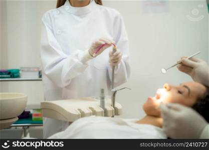 Dental assistant,Dentist and assistant with dental drill and saliva ejector treating patient teeth at dental clinic.
