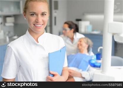 Dental assistant woman smiling at stomatology office dentist with patient