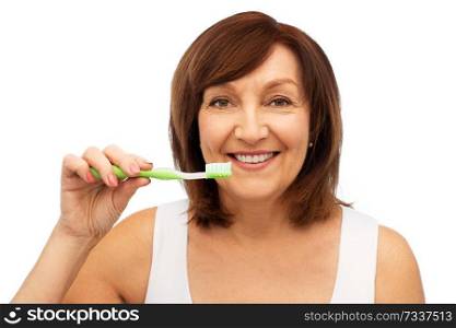 dental care and hygiene people concept - portrait of smiling senior woman with toothbrush brushing her teeth over white background. senior woman with toothbrush brushing her teeth