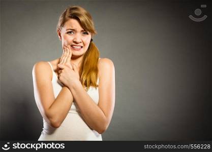 Dental care and toothache. Young woman achy girl suffering from terrible tooth pain, touching pressing her cheek by hand palm.. Woman suffering from tooth pain