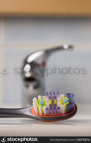 Dental care health concept. Closeup brush toothbrush in bathroom on sink, faucet in the background