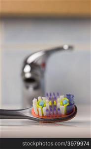 Dental care health concept. Closeup brush toothbrush in bathroom on sink, faucet in the background