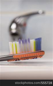 Dental care health concept. Closeup brush toothbrush in bathroom on sink, faucet in the background