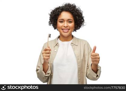 dental care, oral hygiene and people concept - portrait of happy smiling woman holding wooden toothbrush over white background. smiling woman holding wooden toothbrush