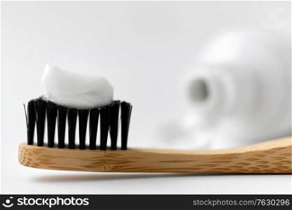 dental care, sustainability and eco living concept - close up of wooden toothbrush with white toothpaste on it. natural wooden toothbrush with toothpaste on it