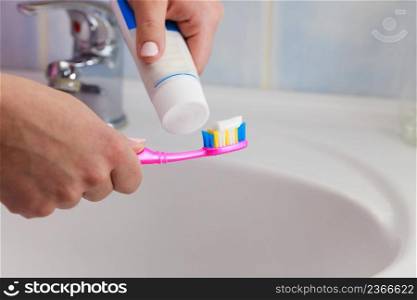 Dental care. Woman hands is holding toothbrush and placing toothpaste on it.. Hand applied toothpaste on toothbrush