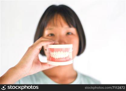 Dental health and child brush teeth concept / Asian child girl holding dental prosthesis , dentures for study