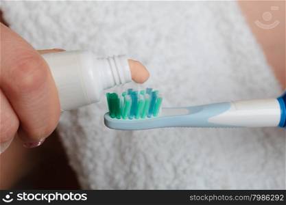 Dental health care. Closeup woman hands holding toothbrush and placing toothpaste on it.
