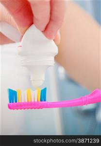 Dental health care. Closeup woman hands is holding toothbrush and placing toothpaste on it.