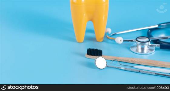 Dental mirror, dentist's tool and plastic teeth on the blue background in dental care concept.