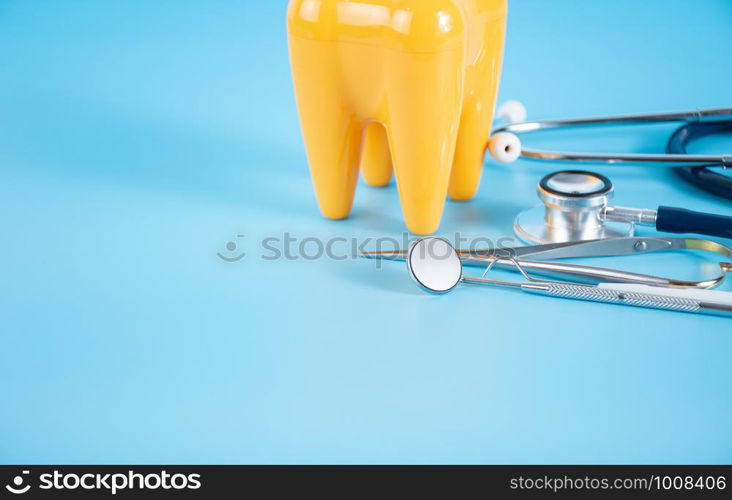 Dental mirror, dentist's tool and plastic teeth on the blue background in dental care concept.