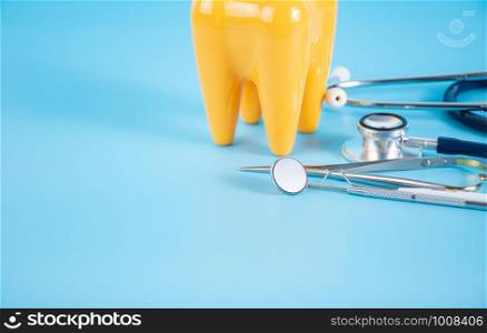 Dental mirror, dentist's tool and plastic teeth on the blue background in dental care concept.
