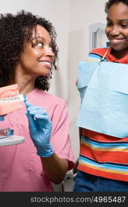 Dental nurse showing boy how to clean teeth properly