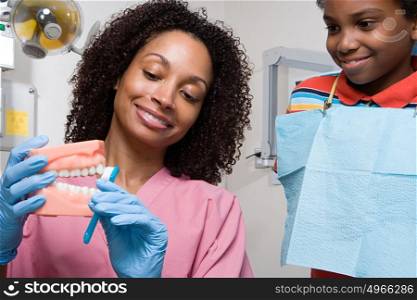 Dental nurse showing boy how to clean teeth properly