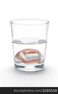 Dental prothesis of a vampire in a glass of water on white background