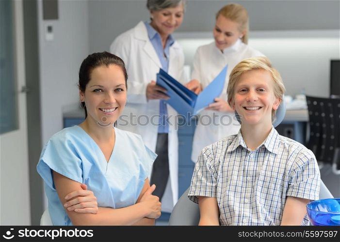 Dental team at stomatology clinic with teenager patient boy smiling