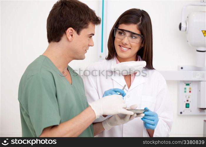 Dental team in office holding sterile tools with x-ray equipment in background