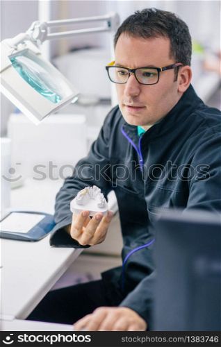 Dental technician or dentist working with tooth dentures in his laboratory