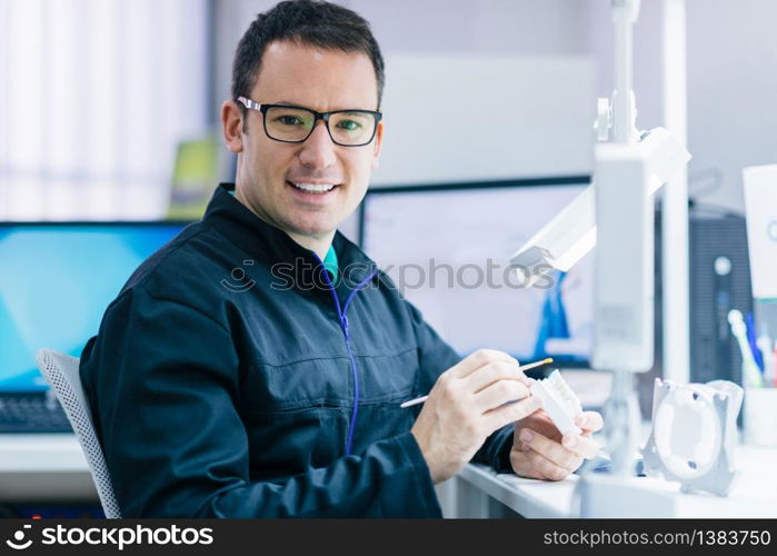 Dental technician or dentist working with tooth dentures in his laboratory