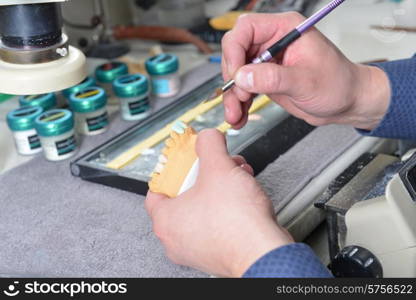 dental technician working on false teeth. table with dental tools.&#xA;