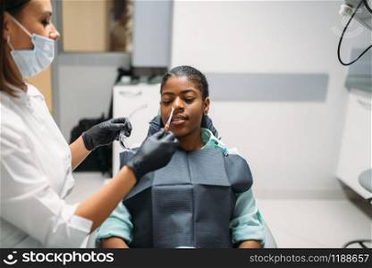 Dentist and female person, visit in dental clinic. Woman in dentistry cabinet, stomatology. Dentist and female person, visit in dental clinic