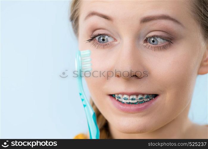 Dentist and orthodontist concept. Young woman smiling cleaning and brushing teeth with braces using toothbrush. Woman smiling cleaning teeth with braces