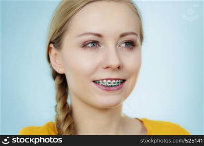 Dentist and orthodontist concept. Young woman teen girl smiling showing teeth with braces, on blue. Young woman showing teeth braces