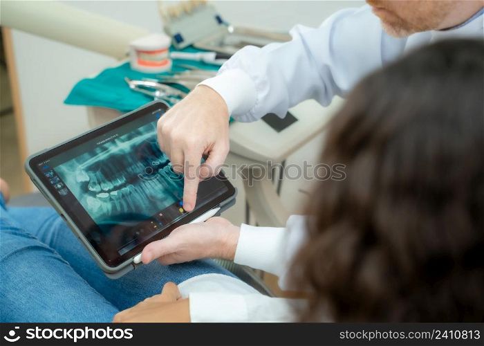Dentist and patient commenting treatments in a tablet application in a consultation,Dentist and patient in dentist office.