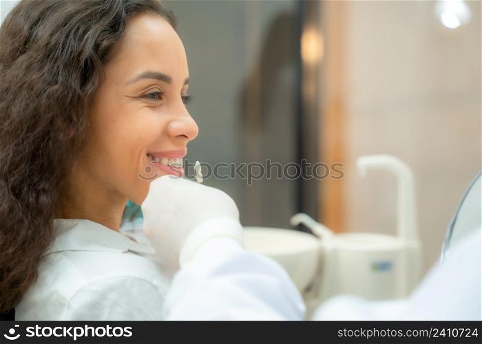 Dentist and patient in dentist office,Doctor compare woman teeth with sampler in dentistry.