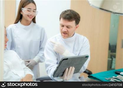 Dentist are showing X-ray on a screen to his patient.