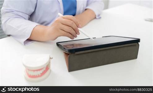 Dentist at dental clinic White healthy tooth with Dental model in oral surgeons discussing jaw x-ray on tablet medicine healthcare oral surgery concept