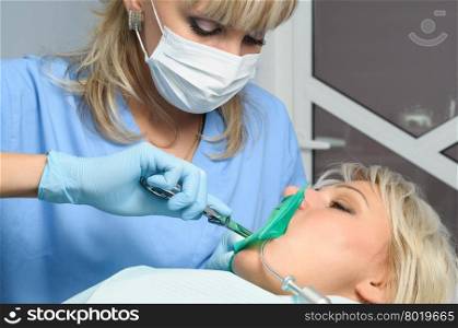 dentist at work with patient, installation of rubber dam or kofferdam