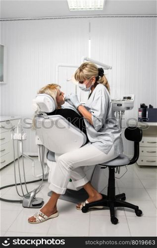dentist at work with patient, using dental drill to cure the tooth