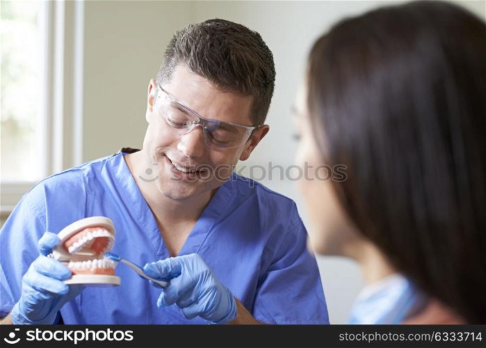 Dentist Demonstrating Correct Use Of Toothbrush To Female Client