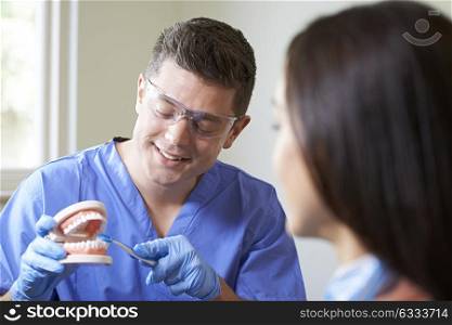 Dentist Demonstrating Correct Use Of Toothbrush To Female Client