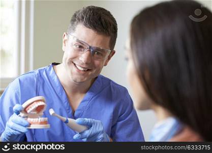 Dentist Demonstrating Use Of Electric Toothbrush To Female Client