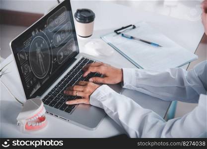 Dentist doctor or nurse in uniform use oral software teeth Xray and typing information medical history form into laptop computer for record document report, tooth model on desk, dentistry concept